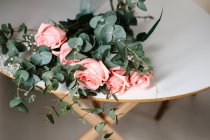 Do acima mencionado buquê de rosas rosa com folhas verdes deitadas na mesa — Fotografia de Stock