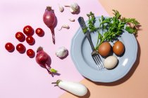 Vista superior de ovos de galinha na placa com garfo contra raminhos de salsa frescos e tomates cereja em dois fundo de cor — Fotografia de Stock
