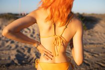 З-за врожаю анонімна молода руда жінка застосовує сонячний лосьйон на пляжі в сонячний день влітку — стокове фото