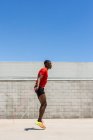 Vista lateral del enérgico atleta afroamericano saltando la cuerda sobre el suelo mientras hace ejercicios durante el entrenamiento en verano - foto de stock