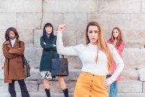 Уверенная женщина показывает бицепс, стоя против группы многорасовых женщин, демонстрирующих концепцию женской силы — стоковое фото