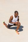 Apto atleta masculino afro-americano fazendo exercício lunge e alongamento pernas enquanto se aquece durante o treinamento no dia ensolarado no verão — Fotografia de Stock