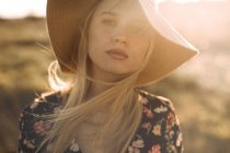 Porträt einer schönen jungen, fröhlichen Frau mit Hut auf dem Land, die in die Kamera lächelt — Stockfoto