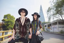 Von unten ernstes stylisches Paar in Hipster-Klamotten, Händchen haltend, während es im Sommer auf der Straße steht — Stockfoto