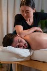 Terapeuta feminina fazendo massagem tailandesa para cliente masculino deitado na mesa no salão de spa — Fotografia de Stock