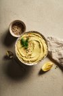 Top view bowl of delicious homemade hummus served on table with slice of lemon and chopped nuts — Stock Photo