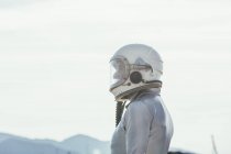 Seitenansicht des Mannes in Raumanzug und Helm, der an sonnigen Tagen in der Natur auf dem Weg steht und wegschaut — Stockfoto