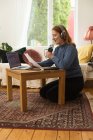 Entzückte Radiomoderatorin nimmt Podcast auf, während sie zu Hause Mikrofon benutzt und Notizen aus Papier liest — Stockfoto
