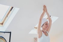 Feminino em pé em Vrksasana pose enquanto pratica ioga no tapete macio e olhos fechados na sala da casa — Fotografia de Stock