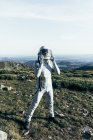 Мужчина-астронавт в скафандре и шлеме стоит на траве и камнях в высокогорье — стоковое фото