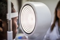 Mulher negra em gabinete de optometria durante o estudo da visão usando um topógrafo de córnea moderna — Fotografia de Stock