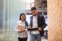 Seriöse multiethnische männliche und weibliche Coworker nutzen Tablet und diskutieren Geschäftsprojekte im modernen Coworking Space — Stockfoto
