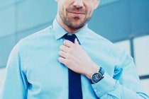 Ernte unkenntlich lächelnde bärtige männliche Führungskraft in formalem Hemd und Krawatte in der Stadt auf verschwommenem Hintergrund — Stockfoto