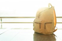 Мандрівний рюкзак розміщений на підлозі біля вікна в залі для відправлення в сучасному аеропорту — стокове фото