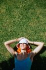 Вид сверху на молодую веселую рыжеволосую женщину, лежащую на траве в солнечный летний день — стоковое фото