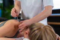 Fisioterapeuta irreconhecível inserindo agulha no ombro de paciente relaxada durante a sessão de acupuntura na clínica — Fotografia de Stock