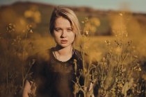 Портрет красивой молодой женщины в сельской местности, смотрящей в камеру среди цветов — стоковое фото