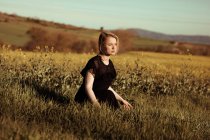 Retrato de uma bela jovem mulher com no campo olhando para longe entre as flores — Fotografia de Stock