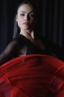 Jeune femme maquillée en rouge et noir exécutant la danse traditionnelle espagnole tout en regardant la caméra — Photo de stock