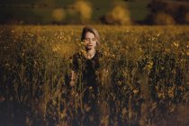 Retrato de una hermosa joven con en el campo con los ojos cerrados entre las flores - foto de stock