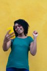 Retrato de una joven africana riendo con un smartphone al aire libre - foto de stock