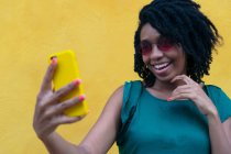 Портрет молодой афроамериканской девушки, смеющейся со смартфоном на открытом воздухе — стоковое фото