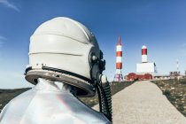 Back view man in spacesuit standing on rocky ground against striped rocket shaped antennas on sunny day — Stock Photo