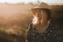 Porträt einer schönen jungen Frau mit Hut auf dem Land, die wegschaut — Stockfoto