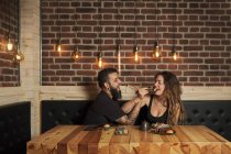 Loving couple eating appetizing sushi while sitting at wooden table in Japanese restaurant — Stock Photo