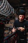 Manillar masculino serio de la fijación del mecánico de la bicicleta mientras que trabaja en taller del servicio de reparación - foto de stock