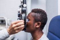 Optometrist beim Einstellen der Optometrie-Ausrüstung während der Untersuchung des Sehvermögens einer schwarzen Frau — Stockfoto