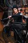 Серьезный мужской механический фиксирующий руль велосипеда во время работы в ремонтной мастерской — стоковое фото