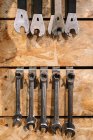 Varias herramientas de metal colgando en filas en la pared de madera en servicio de reparación de bicicletas en mal estado - foto de stock