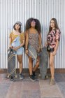 Три красивые молодые женщины разных рас с длинными досками, смотрящие в камеру — стоковое фото