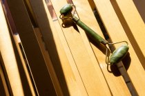 Da sopra rullo di giada per procedura spa collocato su panca di legno a casa — Foto stock