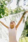Contenuto ragazza adolescente in abito da balletto che gioca con un panno trasparente sul prato nel parco nella giornata di sole — Foto stock