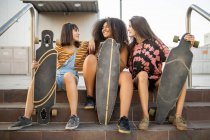 Tres mujeres jóvenes de diferentes razas con sus largas tablas divirtiéndose y sonriendo - foto de stock