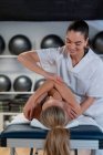Female therapist in white robe massaging woman during osteopathy session in clinic — Stock Photo
