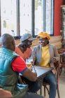 Compagnia di contenuti Amici afroamericani che si riuniscono a tavola con la birra al bar e parlano tra loro — Foto stock