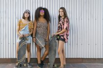Three beautiful young women of different races with their long board boards looking at the camera — Stock Photo