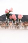Roses roses à l'intérieur de vases en verre placés sur la terrasse à l'extérieur — Photo de stock