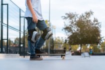Crop Adolescente in tenuta protettiva con skateboard in skate park e distogliendo lo sguardo — Foto stock