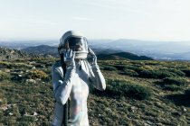 Astronauta macho en traje espacial y casco de pie sobre hierba y piedras en las tierras altas - foto de stock