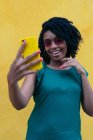 Портрет молодой чернокожей девушки, смеющейся со смартфоном на открытом воздухе — стоковое фото