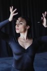 Jovem mulher graciosa em vestuário preto com braços levantados jogando castanholas enquanto executa dança tradicional espanhola e olhando para longe — Fotografia de Stock