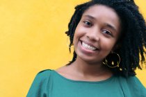 Close upside portrait of beautiful smiling young Black woman leaning against wall outside — Stock Photo