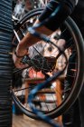 Обрізати анонімного чоловіка механіка з брудними руками фіксуючи касету передач колеса в майстерні ремонту — стокове фото