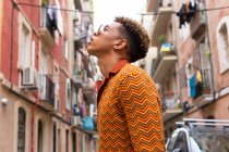 Vue latérale à angle bas de jeunes touristes ethniques masculins confiants regardant loin tout en explorant les vieilles rues étroites de la ville de Barcelone — Photo de stock