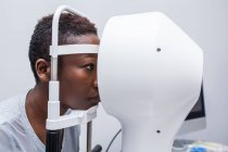 Donna nera in gabinetto di optometria durante lo studio della vista usando un topografo corneale moderno — Foto stock