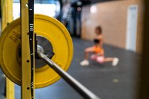 From above side view of anonymous female athlete performing forward lunge during workout with weights against barbell in gym — Stock Photo
